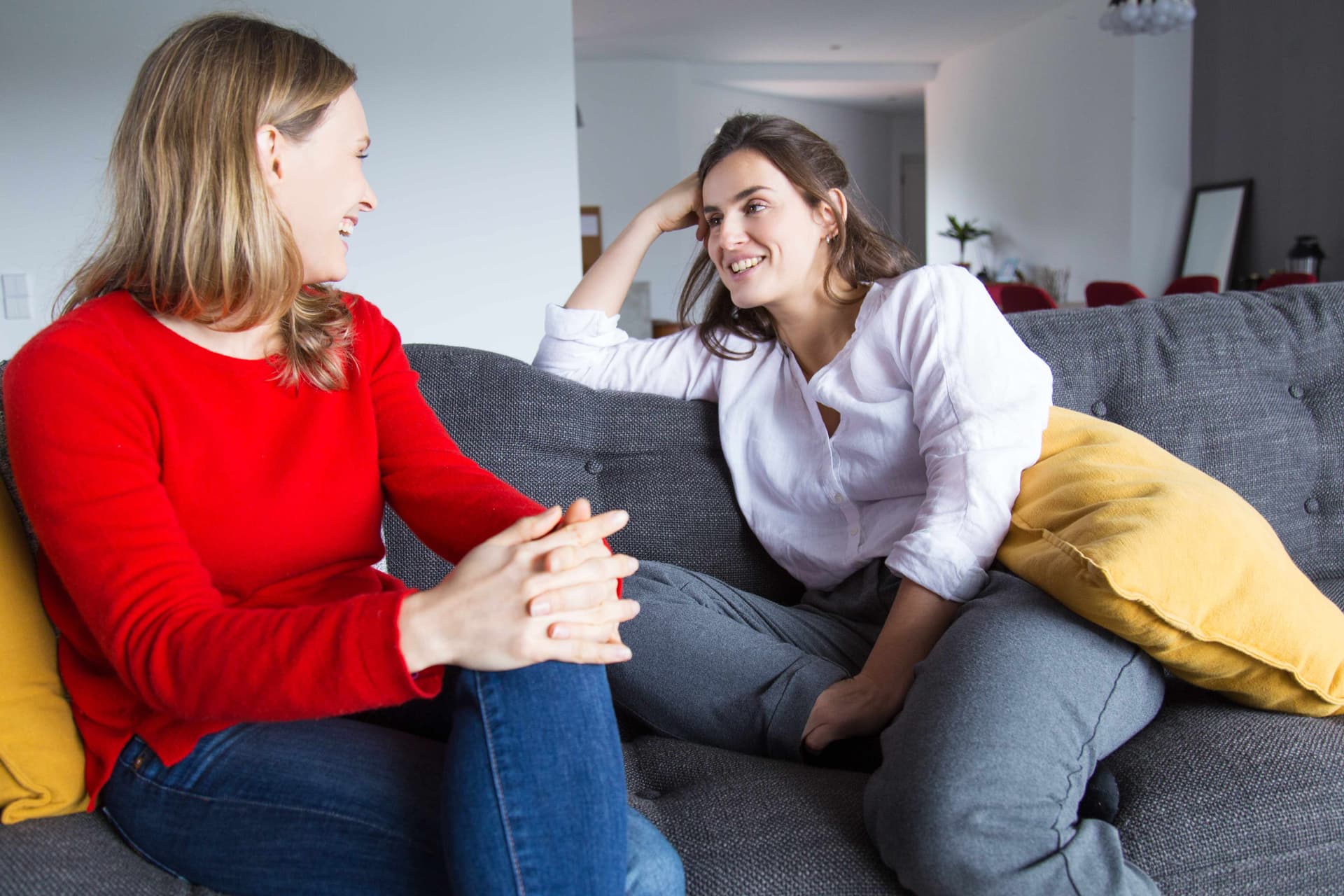 Zwei Frauen im Gespräch auf einem Sofa im Wohnzimmer