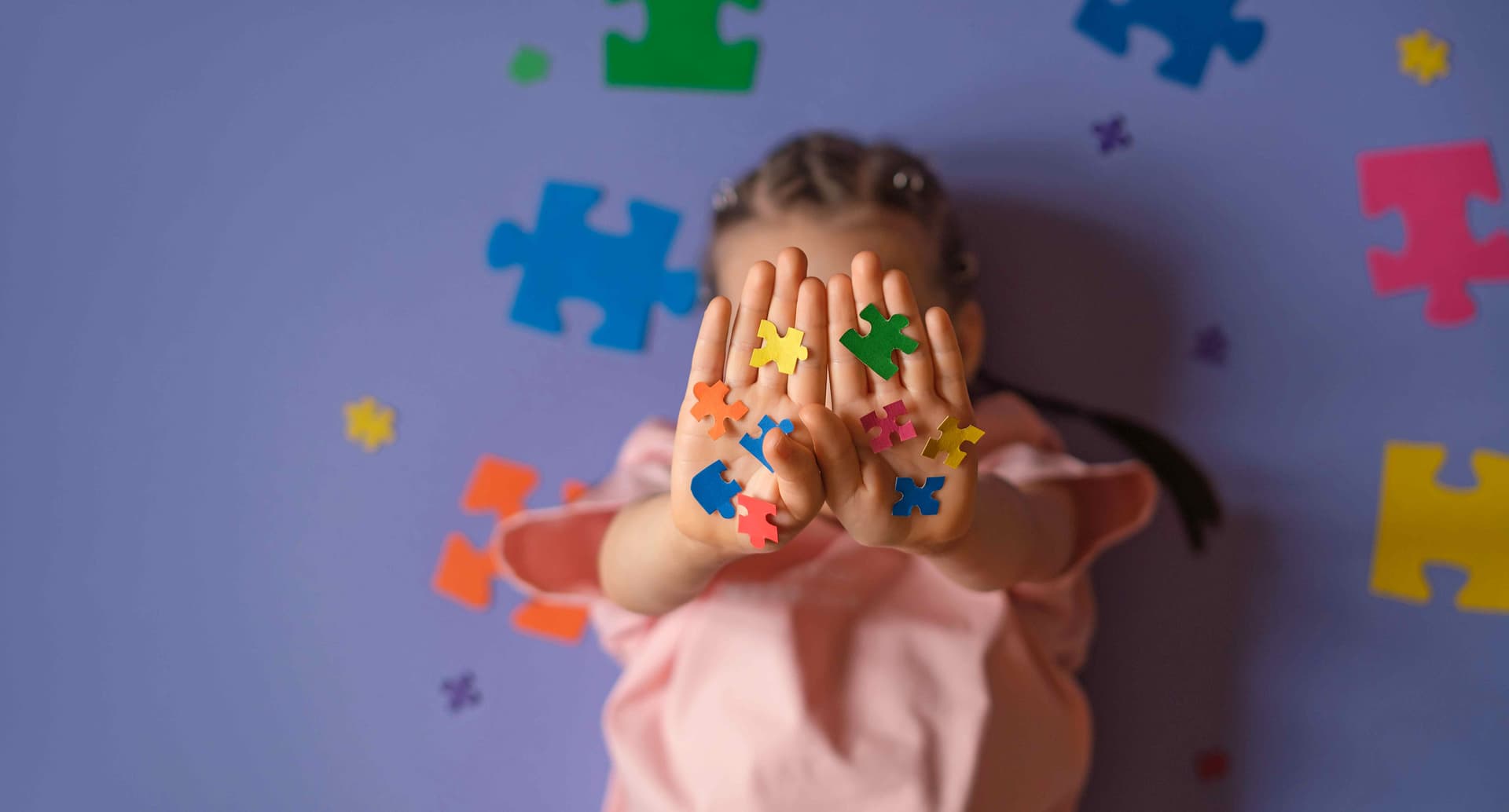 Kind mit bunten Puzzleteilen als Symbol für Vielfalt und Teilhabe
