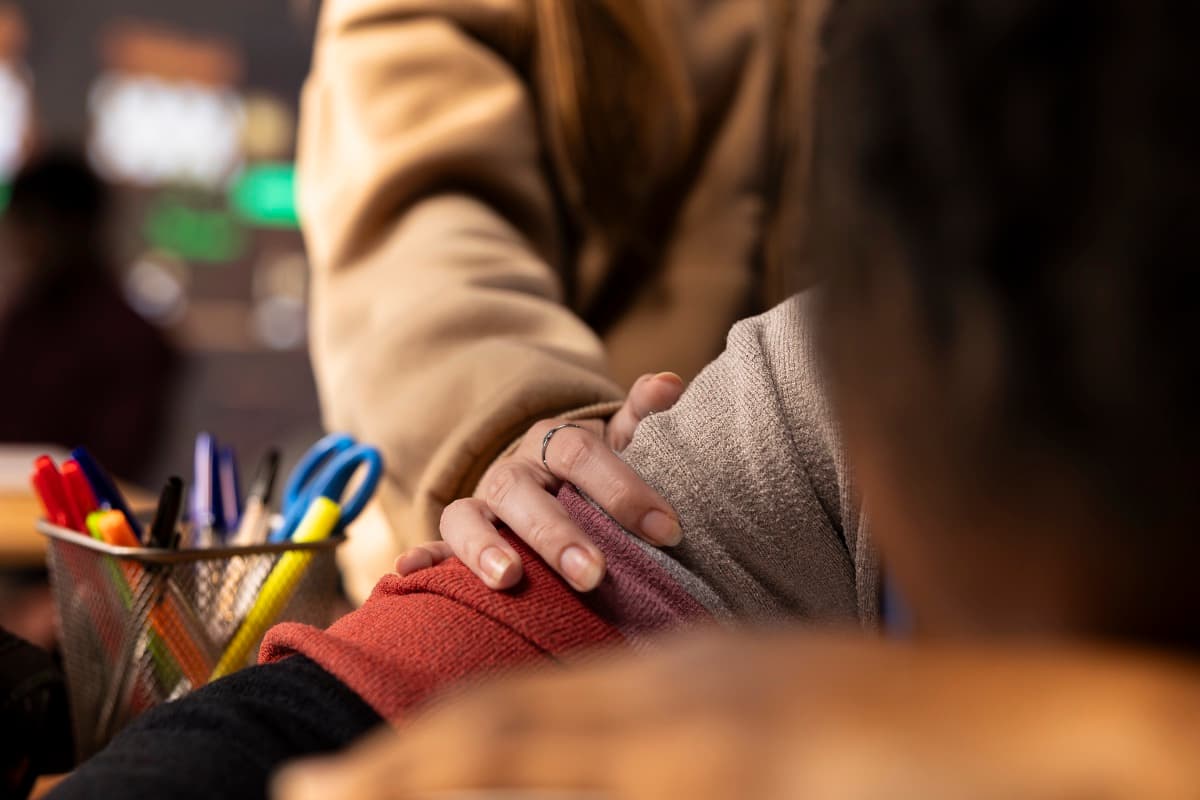 Eine Hand ruht unterstützend auf dem Arm einer Person als Symbol für ambulante Hilfe, die im Alltag Nähe schenkt