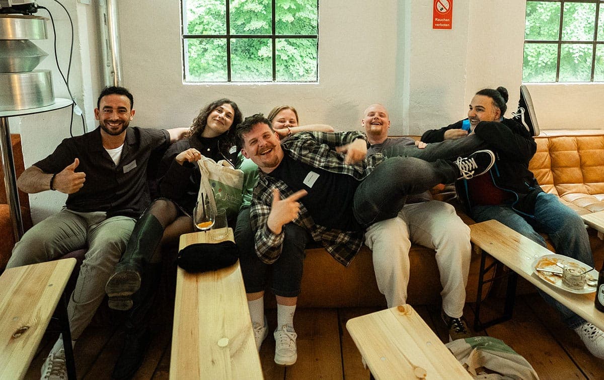 Das Team der Jetzt Jugendhilfe lacht gemeinsam auf einer Couch bei einem Teamevent