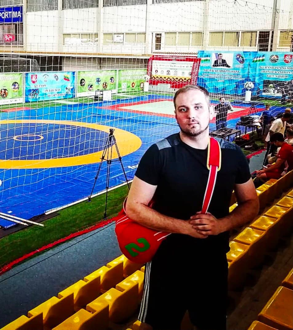 Wladimir Zimmermann mit roter Sporttasche und Ringergurt bei einem Turnier in der Sporthalle